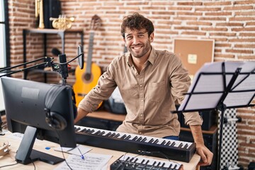 Young man musician smiling confident sitting at music studio