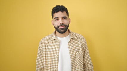Obraz premium Young hispanic man smiling confident standing over isolated yellow background