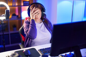 Young beautiful plus size woman streamer stressed using computer at gaming room