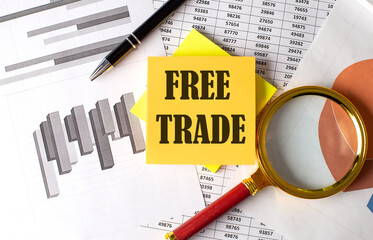 FREE TRADE text on a sticky on the graph background with pen and magnifier