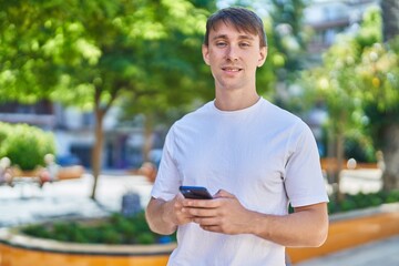 Young caucasian man smiling confident using smartphone at park