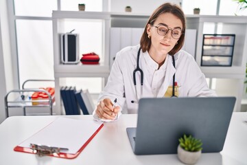 Young caucasian woman doctor using laptop working at clinic