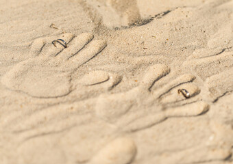 Fototapeta na wymiar two hand prints with wedding rings on tropical sand beach, outdoor beach wedding concept