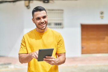 Young hispanic man smiling confident using touchpad at street