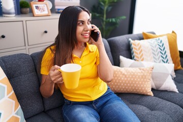 Young beautiful arab woman talking on smartphone drinking coffee at home