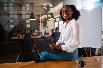 Black businesswoman working on laptop. Portrait of beautiful businesswoman sitting on the desk.