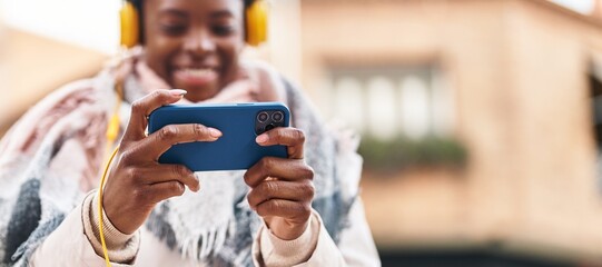 African american woman smiling confident playing video game at street
