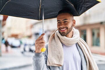 African american man smiling confident holding umbrella at street