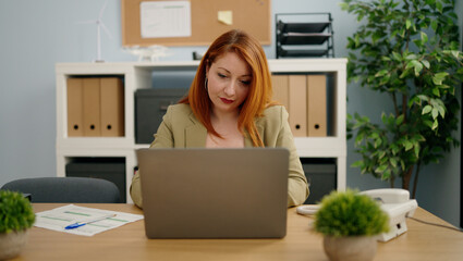 Young redhead woman business worker using laptop working at office