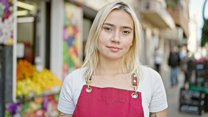 Young beautiful hispanic woman wearing apron with relaxed expression at fruit store