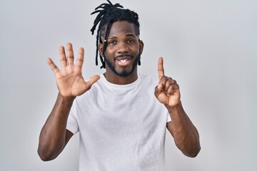 Fototapeta premium African man with dreadlocks wearing casual t shirt over white background showing and pointing up with fingers number six while smiling confident and happy.