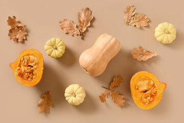 Autumn composition of pumpkins, gourd and falled oak leaves on beige background. Top view. Thanksgiving Day.