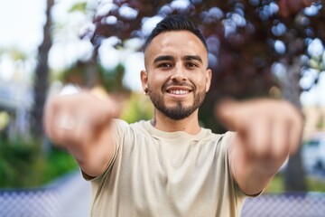 Young hispanic man smiling confident pointing with fingers at park