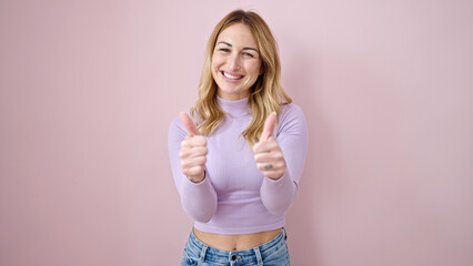 Young beautiful hispanic woman smiling with thumbs up over isolated pink background