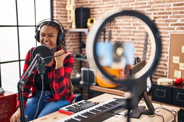 African american woman with braids recording music tutorial with smartphone at home pointing thumb up to the side smiling happy with open mouth