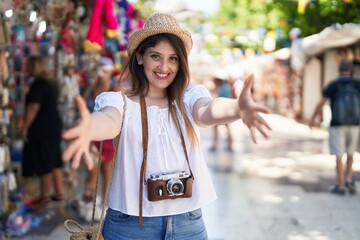 Young brunette woman on summer vacation looking at the camera smiling with open arms for hug....