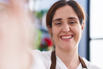 Young woman florist smiling confident make selfie by camera at florist shop