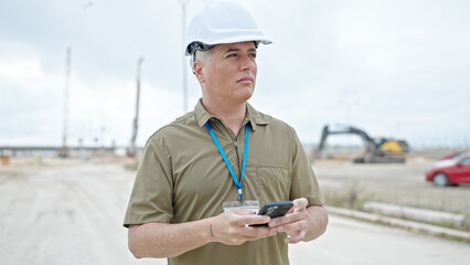 Young caucasian man architect using smartphone at construction place