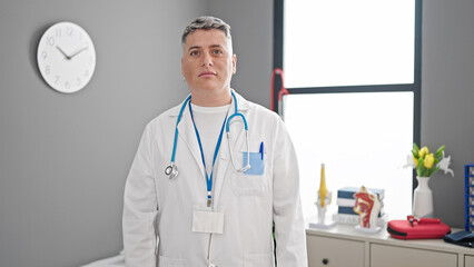 Young caucasian man doctor standing with serious expression at the clinic