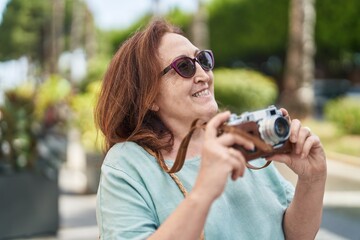 Senior woman tourist smiling confident holding camera at street