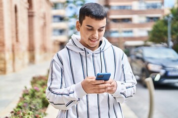 Young man smiling confident using smartphone at street