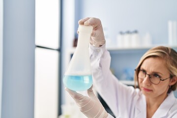 Fototapeta premium Young blonde woman scientist holding test tube at laboratory