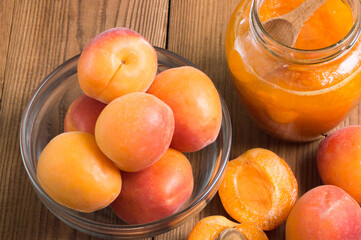 Jam from apricots in a glass jar with ripe apricot on the wooden table