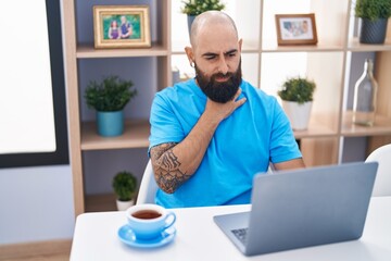 Young bald man using laptop suffering for throat pain at home