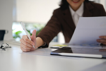 Hand of young businesswoman writing on paper, preparing economic report at office desk