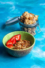 green bowl and glass jar with granola cookies, on blue background