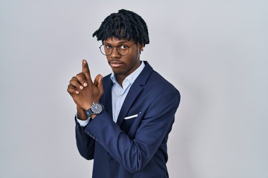 Young african man with dreadlocks wearing business jacket over white background holding symbolic gun with hand gesture, playing killing shooting weapons, angry face