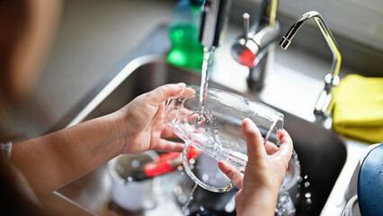 Young beautiful hispanic woman washing plates at the kitchen