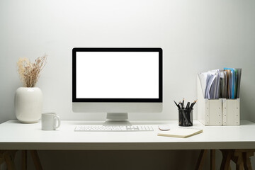 Naklejka premium Blank empty desktop computer, potted plant and books on white table. White screen for your advertising text message 