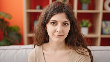 Young beautiful hispanic woman sitting on sofa with relaxed expression at home