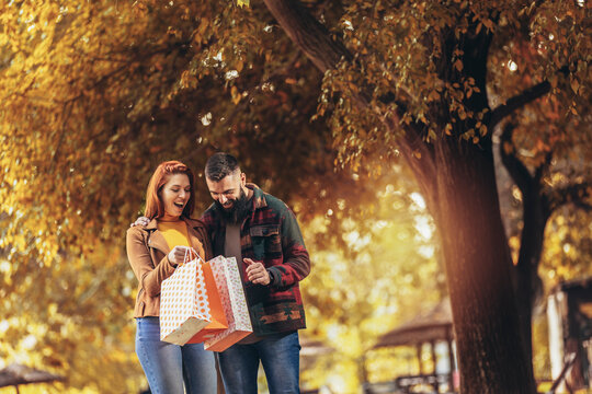 Happy couple with shopping bags in autumn park