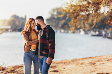 Happy young couple in love holding hands and walking on coast near river.