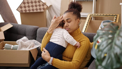 Mother and son tired sitting on sofa holding baby at new home