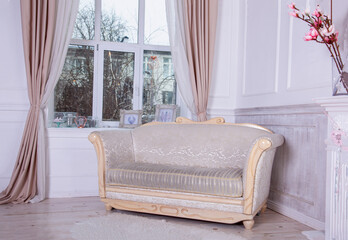 An old sofa with wooden planks by the window. Empire style furniture. Light white room interior.