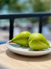 two juicy yellow-green pears on a white plate on a bright sunny day, selective focus