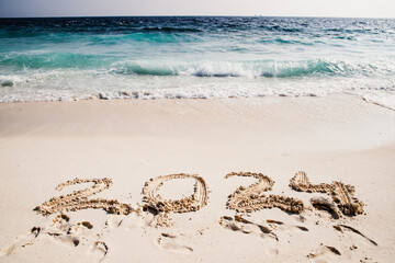 2024 written in white sand on tropical beach, happy New Year