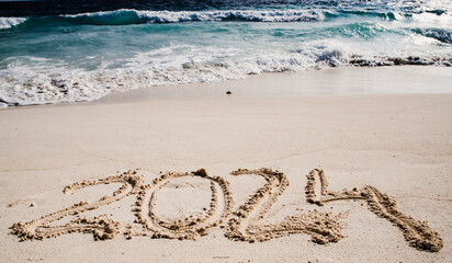 2024 written in white sand on tropical beach, happy New Year