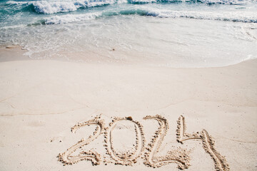 2024 written in white sand on tropical beach, happy New Year