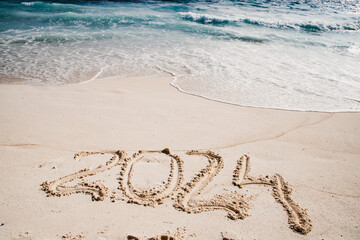2024 written in white sand on tropical beach, happy New Year