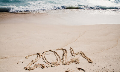 2024 written in white sand on tropical beach, happy New Year