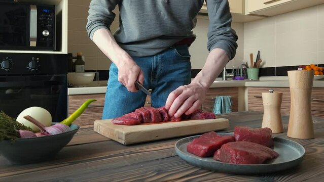 Slicing raw deer meat into pieces for ragout in the kitchen