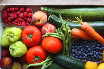 Wooden crate full of healthy seasonal fruit and vegetable. Top view, wooden background.