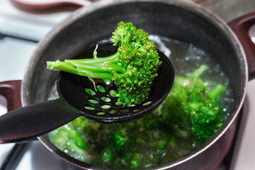 Boiling raw brocoli in water  in metal boiling pan. Green vegetables cooking 