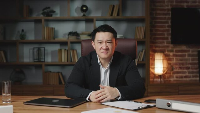 Middle-aged asian financial director feeling stress and despair because of losing tender in contemporary working place. Furious man clenching fists and gritting teeth in frustration.
