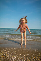 Venice, Italy - 06.06.2023: little girl with a big smile is jumping in the sea. Venice, Italy
