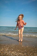 Venice, Italy - 06.06.2023: little girl with a big smile is jumping in the sea. Venice, Italy
